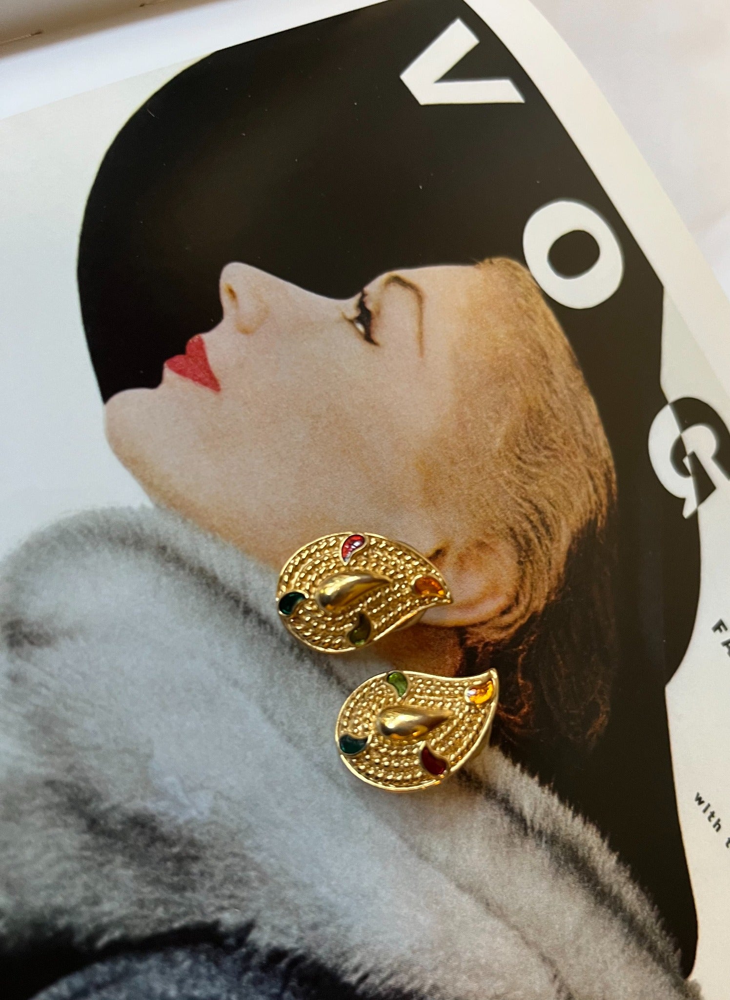 Close-up vintage gold-tone paisley earrings with multicolor enamel accents